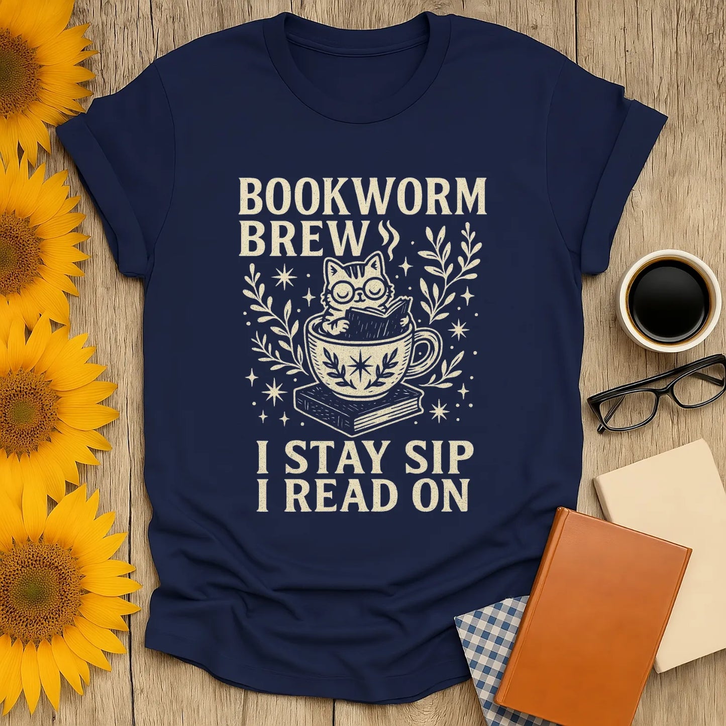 Navy Bookworm Brew t-shirt with a cat in a teacup and text: 'I Stay Sip I Read On'—perfect for cozy book lovers.