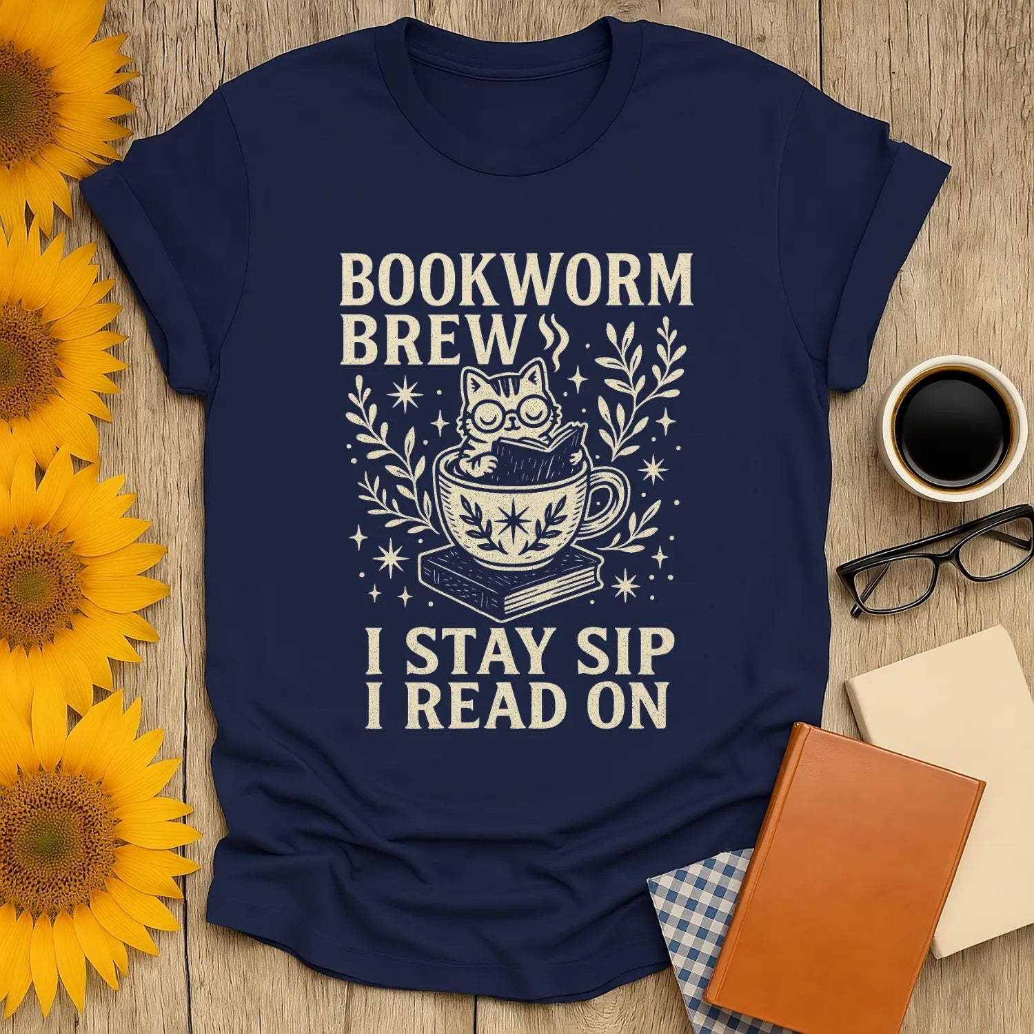 Navy Bookworm Brew t-shirt with a cat in a teacup and text: 'I Stay Sip I Read On'—perfect for cozy book lovers.