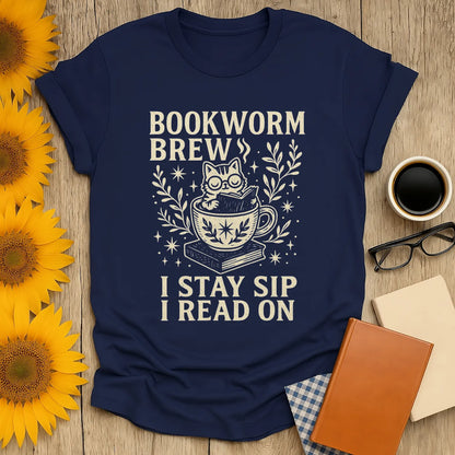 Navy Bookworm Brew t-shirt with a cat in a teacup and text: 'I Stay Sip I Read On'—perfect for cozy book lovers.