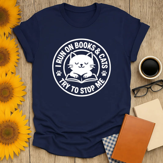 Cozy navy t-shirt with a cute cat and text 'I RUN ON BOOKS & CATS TRY TO STOP ME' perfect for book lovers and cat enthusiasts.