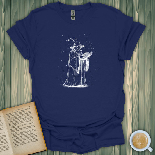 The Wizard's Grimoire T-Shirt for book lovers, featuring a wizard reading a spellbook on a navy blue tee.