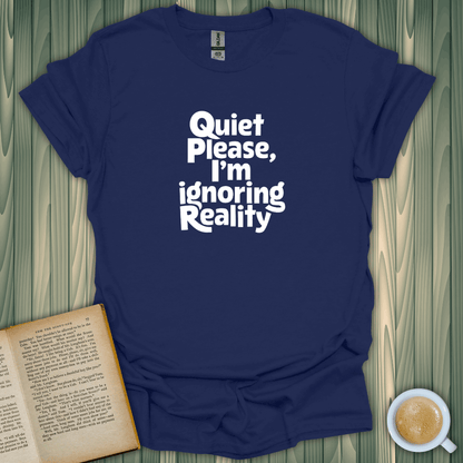 Blue unisex t-shirt with "Quiet, I'm Ignoring Reality" text, perfect for book lovers and cozy vibes.