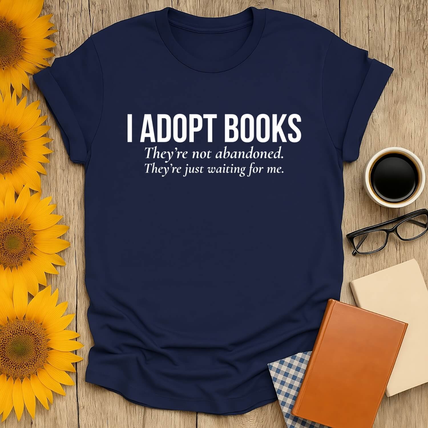 Book lover t-shirt featuring 'I Adopt Books' slogan, styled with sunflowers and books, perfect for bibliophiles.