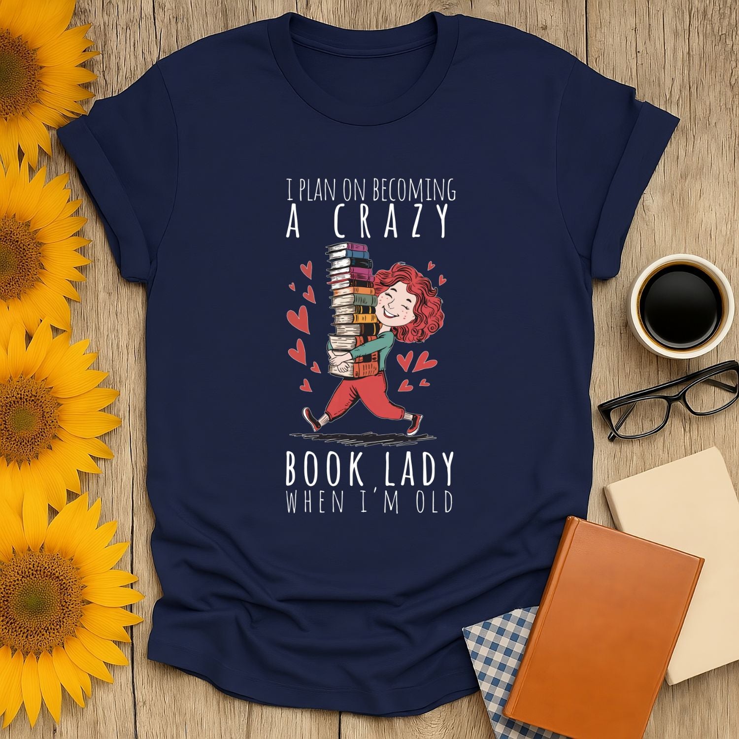 Funny book lover t-shirt with a woman carrying stacked books and the quote 'I plan on becoming a crazy book lady when I'm old'.