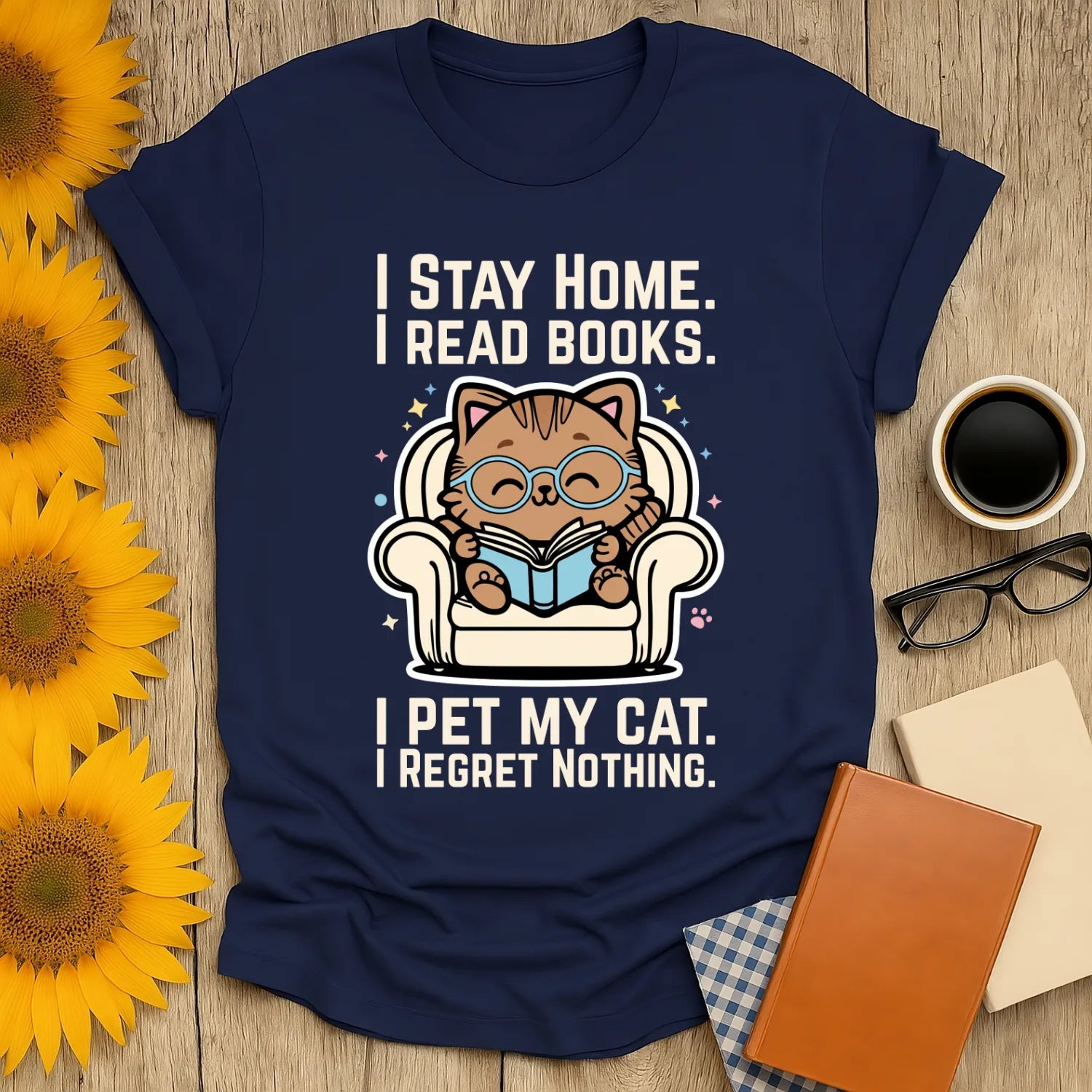 Illustration of a cute cat in glasses reading on a couch with text: "I Stay Home. I Read Books. I Pet My Cat. I Regret Nothing" on a navy Starry Cat Reader T-Shirt.
