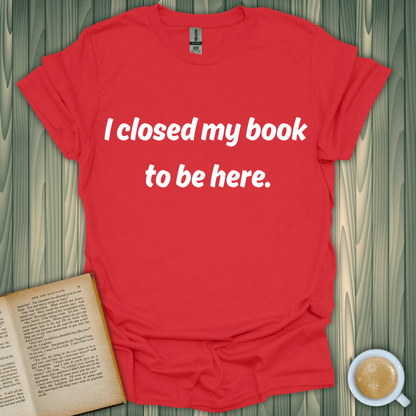 Red unisex t-shirt featuring the phrase 'I closed my book to be here,' perfect for book lovers. Made of 100% ring-spun cotton.