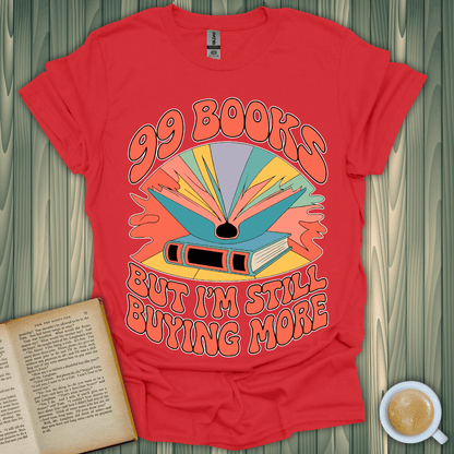 Red t-shirt featuring colorful design with text '99 Books But I'm Still Buying More', perfect for book lovers.