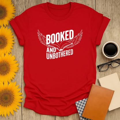 Red t-shirt for book lovers reading 'Booked and Unbothered' with wings, perfect cozy gift for readers and cat lovers.