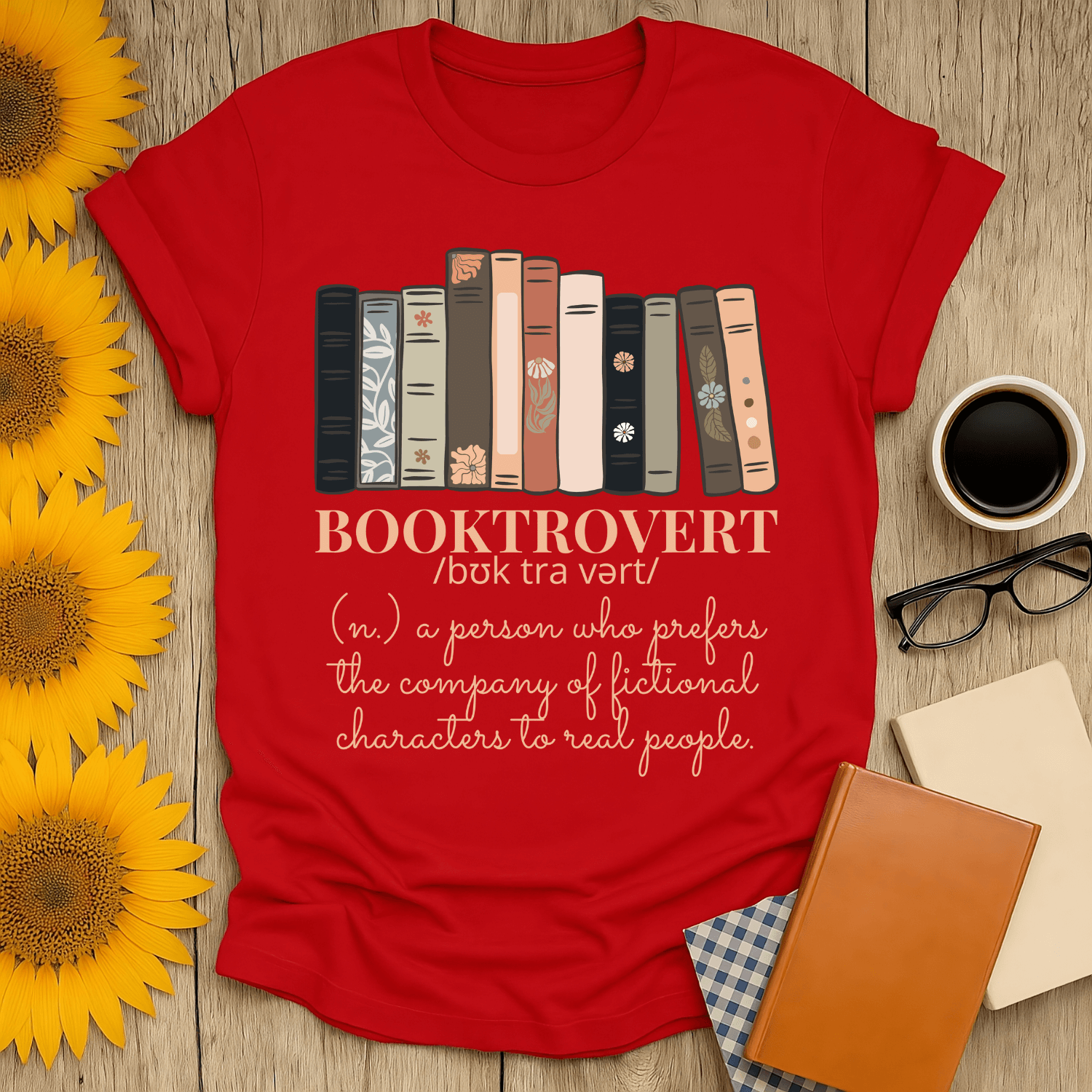 Booktrovert t-shirt in red, featuring a fun definition for book lovers, surrounded by sunflowers and books.
