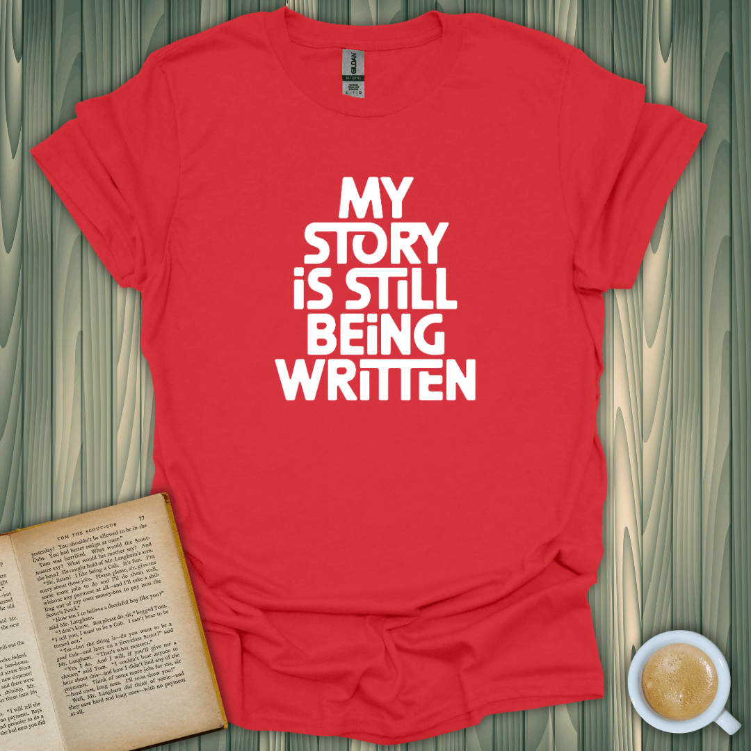 Red unisex t-shirt with "My Story is Still Being Written" design, perfect for book lovers.