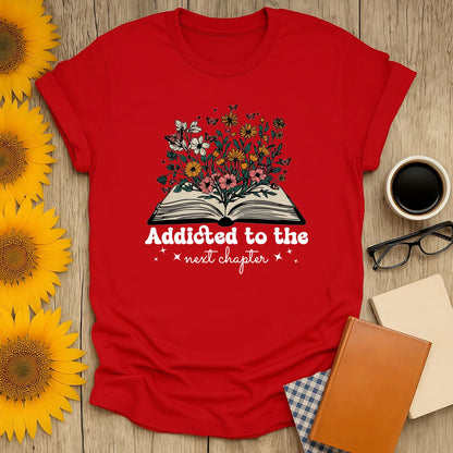 Addicted to the next chapter tee, blooming flowers and open book design, perfect for cat, coffee, and tea-loving bookworms.