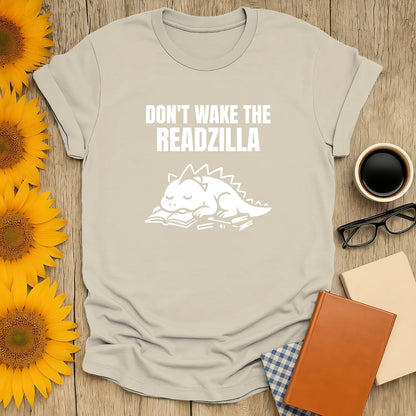 Light gray t-shirt with a sleeping dinosaur on a book and the text 'Don't Wake the Readzilla', perfect gift for book lovers.
