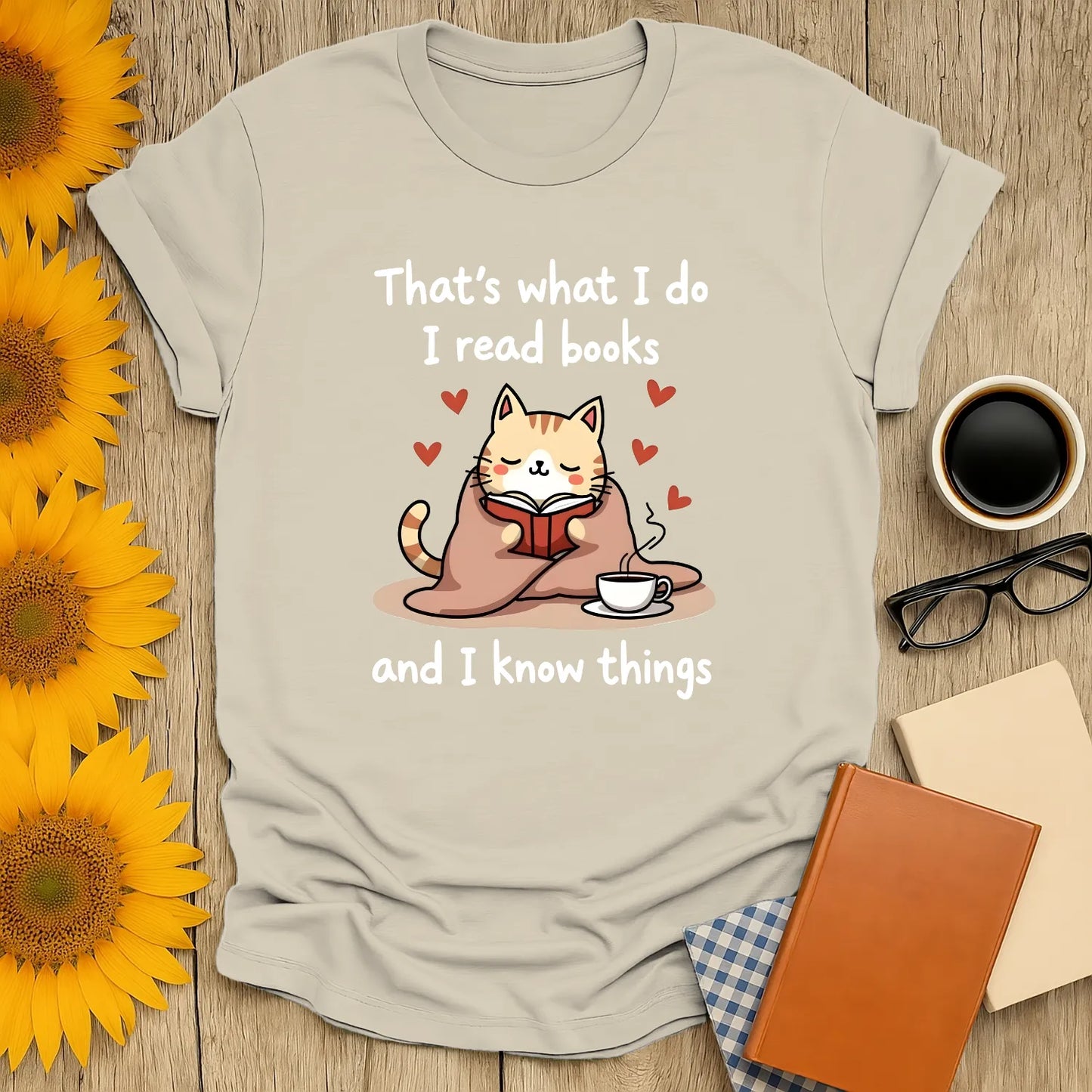 Cozy kitty reading a book with a cup, saying 'That's what I do I read books and I know things'—perfect gift for cat-loving bookworms.