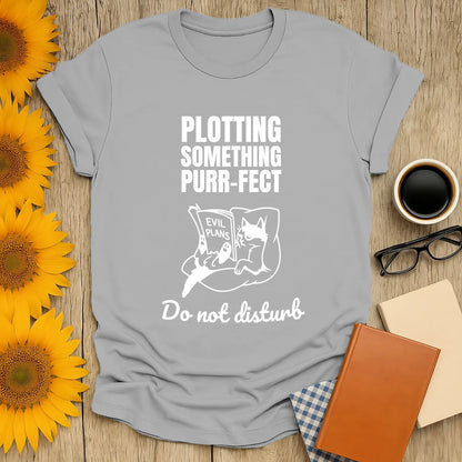 Funny cat-themed shirt with text 'Plotting Something Purr-fect' and a cat reading 'Evil Plans'; perfect for book lovers.