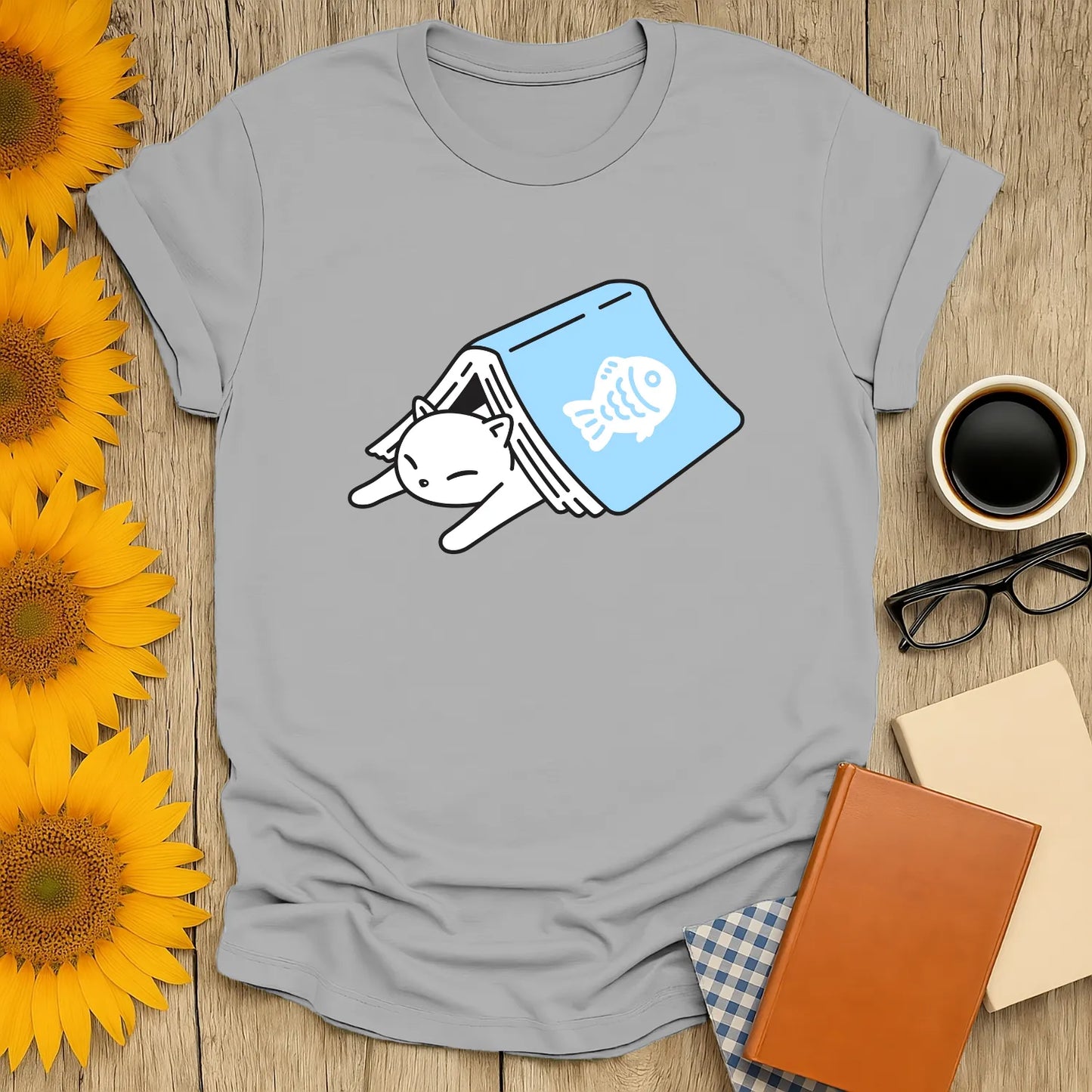 Cozy gray cat reading t-shirt featuring a sleepy cat in a book with a fish print—ideal for book lovers and cat enthusiasts!