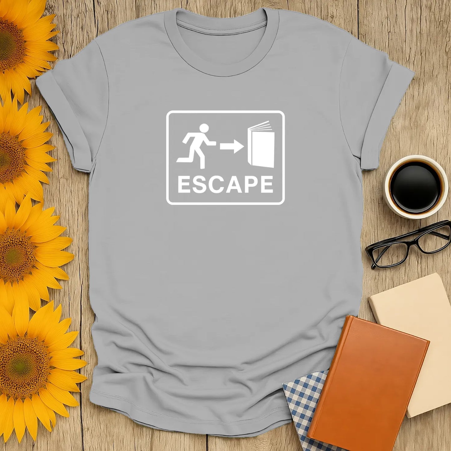 Light gray book lover shirt featuring a playful 'Escape' graphic with a running figure leading to an open book, perfect for cozy reading.