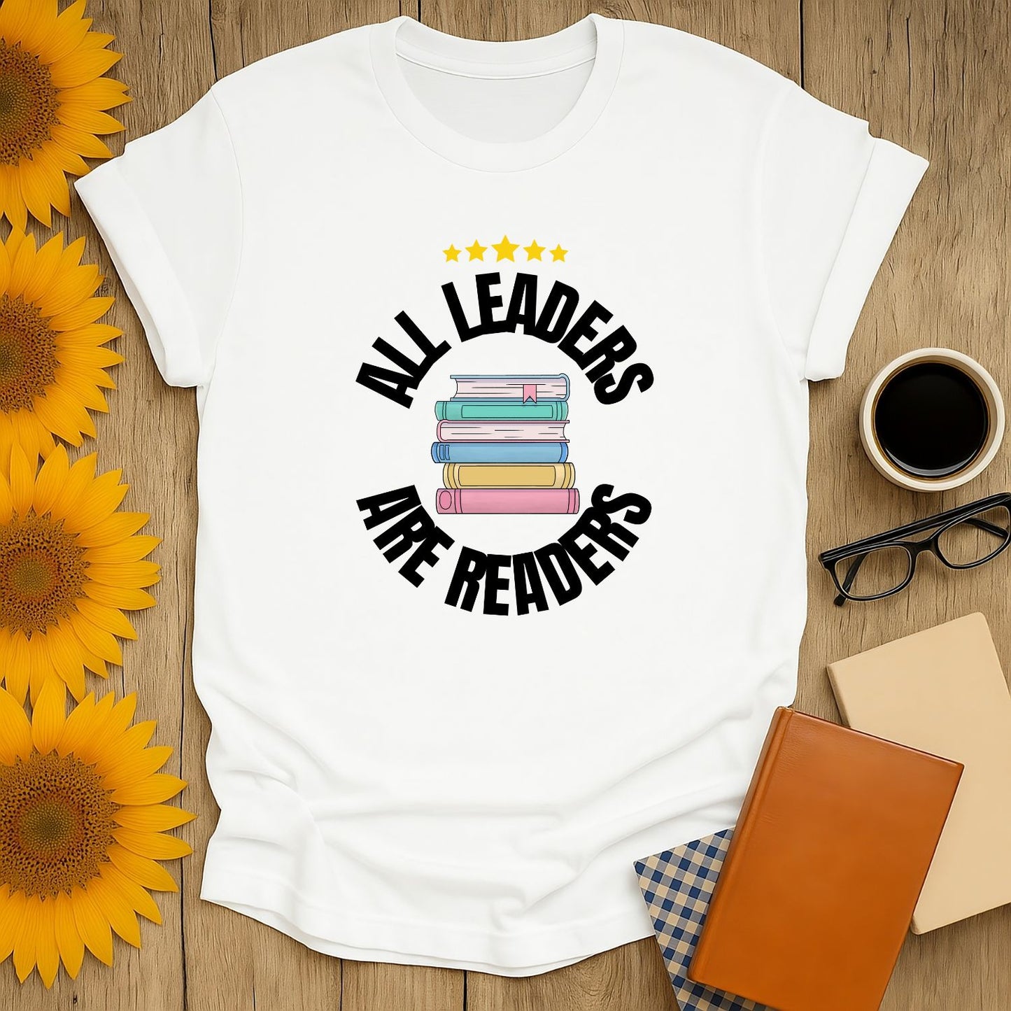 Unisex Leaders Are Readers T-Shirt with stacked books, perfect gift for book lovers who adore cats, coffee, and cozy reading.