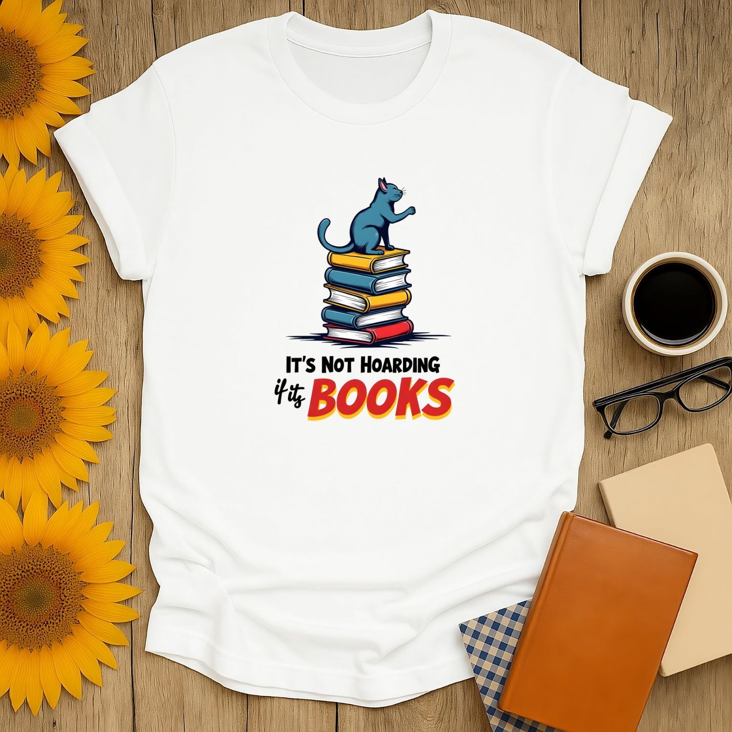 Unisex Not Hoarding, Just Books t-shirt for book lovers, featuring a cat on stacked books. Made of 100% ring-spun cotton.